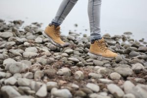 Mujer caminando entre las piedras con zapatillas impermeables
